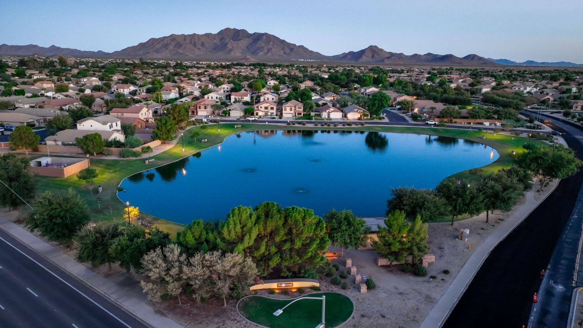 Aerial view over the Sun Groves community lake with mountains on the horizon